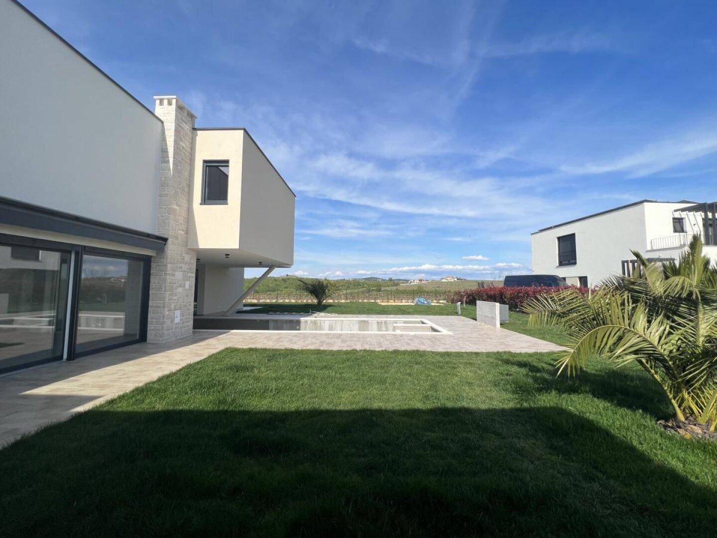 Gepflegter Gartenbereich mit Rasenfläche und Blick auf die umliegende Landschaft und Nachbarhäuser.