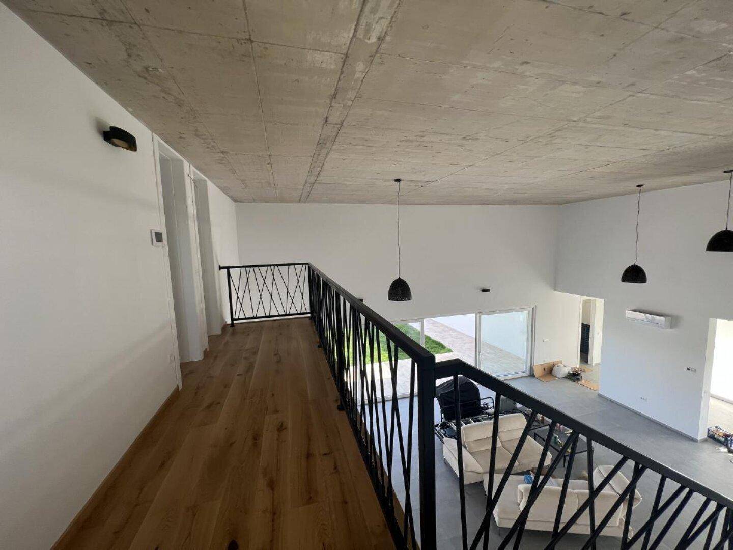 Offener Wohnbereich mit Galerie, hohen Decken und Holzboden im oberen Bereich.