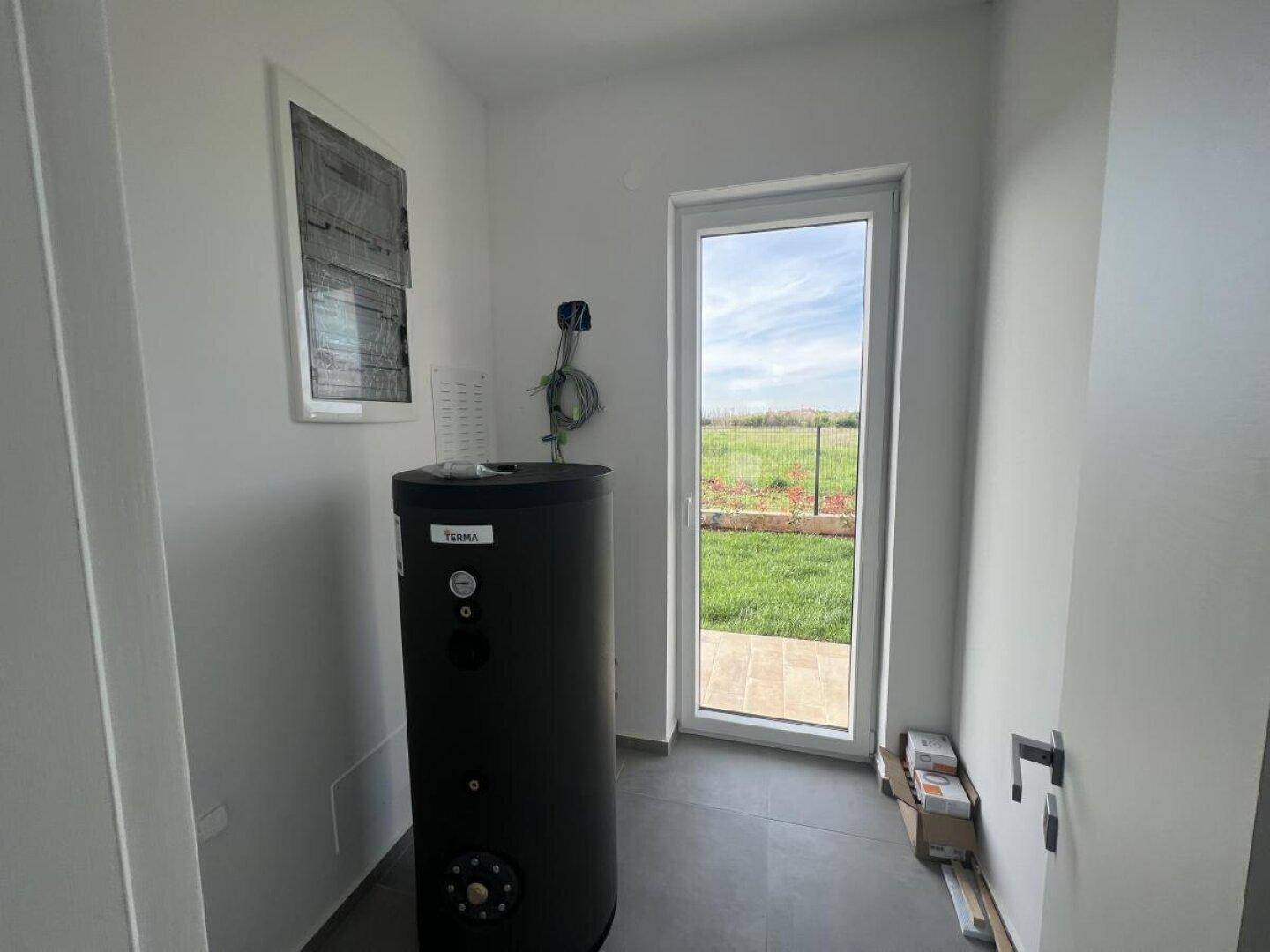 Hauswirtschaftsraum mit Warmwasserspeicher und Fenster mit Blick ins Grüne.