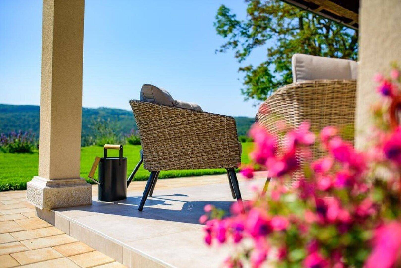 Komfortabler Sessel auf der Terrasse mit Blick auf die hügelige, grüne Landschaft.