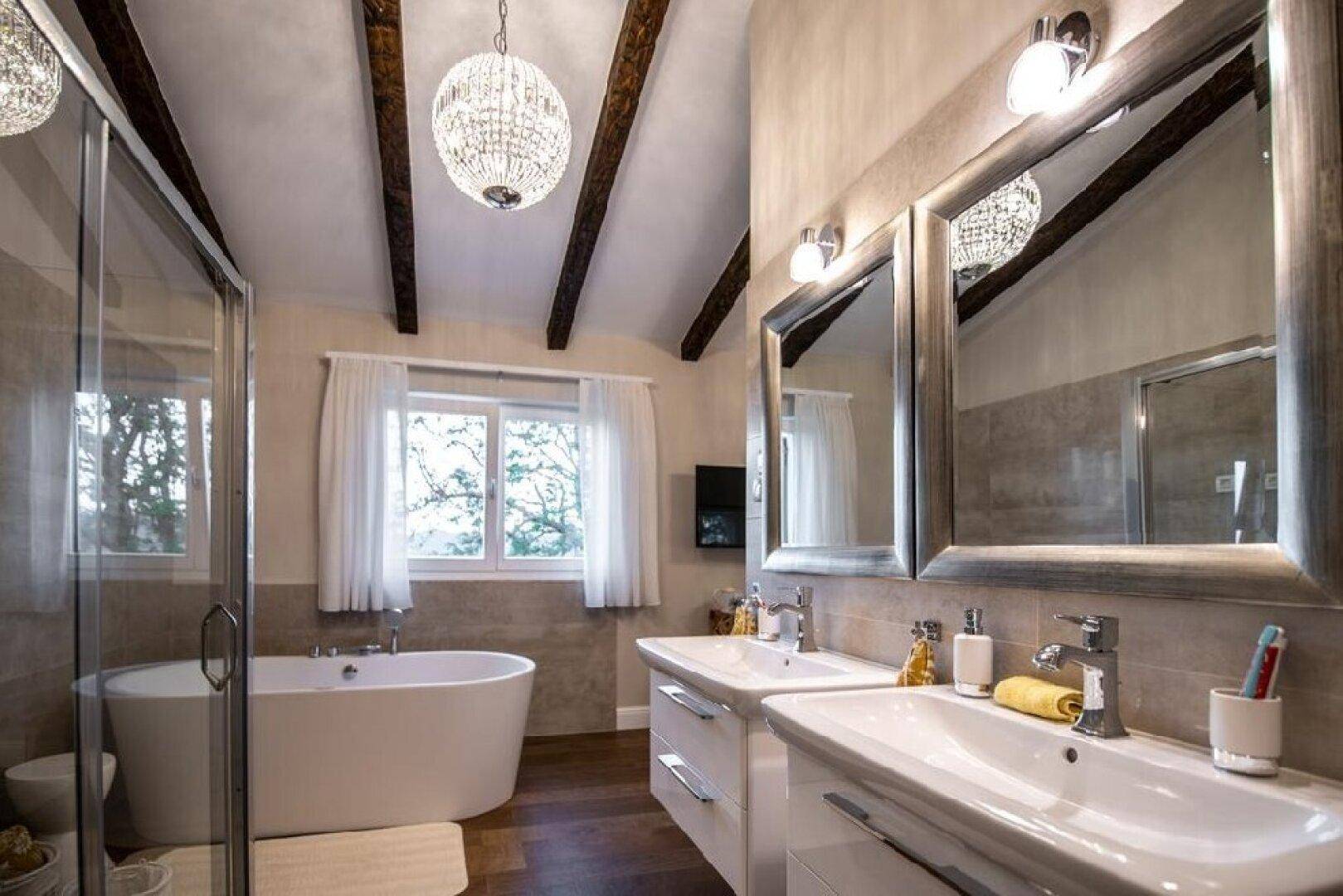 Elegantes Badezimmer mit freistehender Badewanne, Doppelwaschbecken und Fenster.