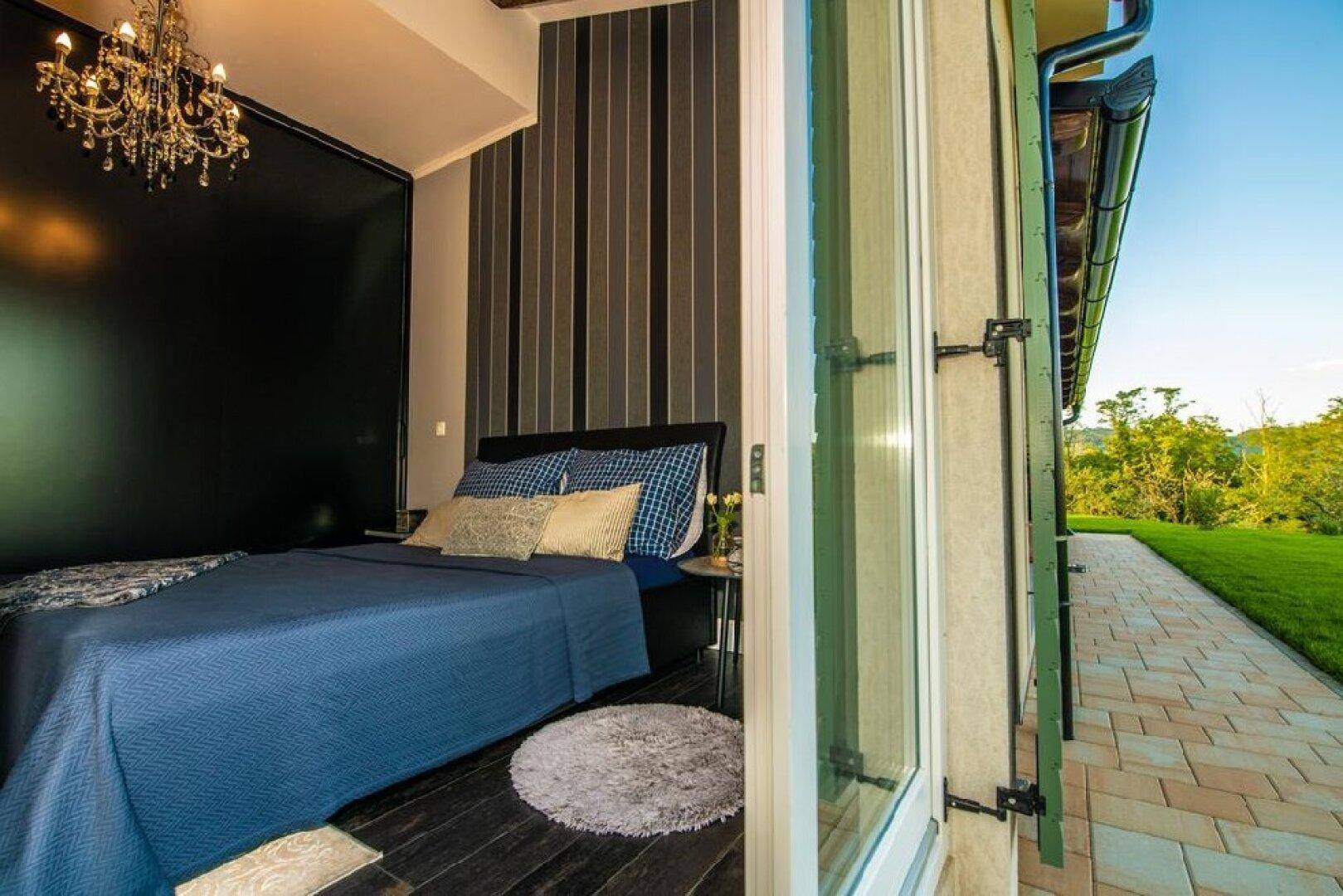 Schlafzimmer mit direktem Zugang zu einem gepflasterten Weg und Blick ins Grüne.