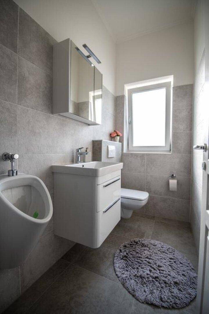 Modernes Gäste-WC mit Urinal, Waschbecken und Spiegelschrank.