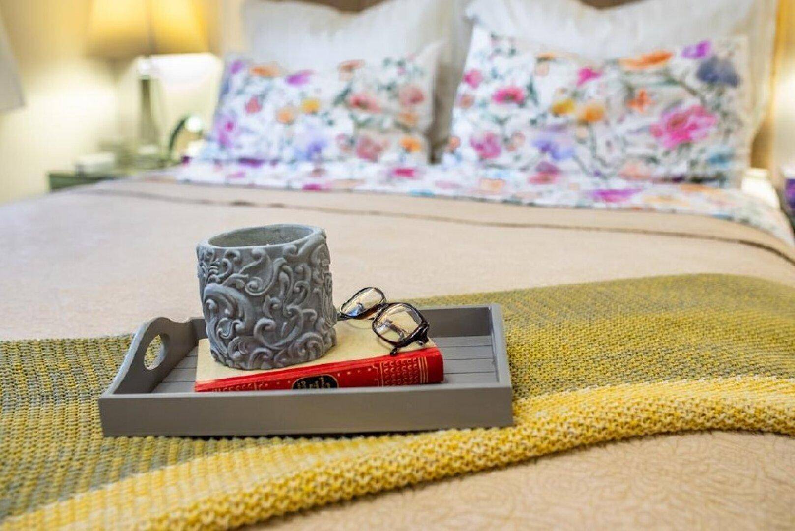 Nahaufnahme eines Bettes mit floral gemusterter Bettwäsche und dekorativer Decke.