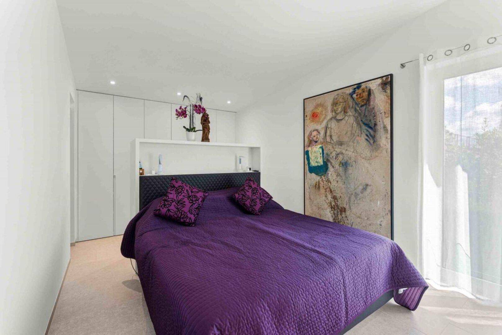 Geräumiges Schlafzimmer mit großem Bett, Einbauschränken und moderner Kunst an der Wand.