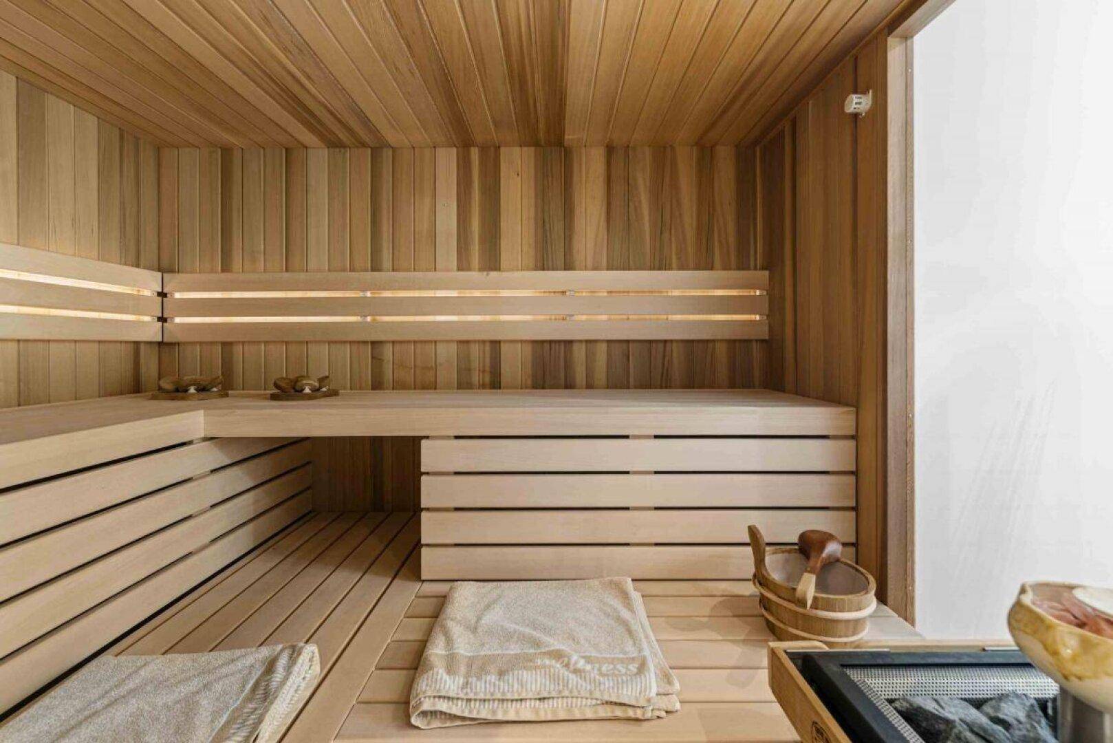 Gemütliche Holzsauna mit mehreren Bänken und traditionellem Saunaofen für Entspannung.