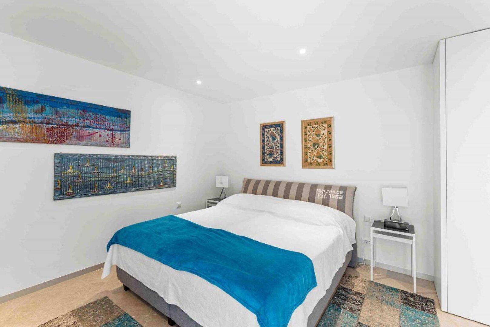 Geräumiges Schlafzimmer mit Doppelbett und dekorativen Kunstwerken an den Wänden.