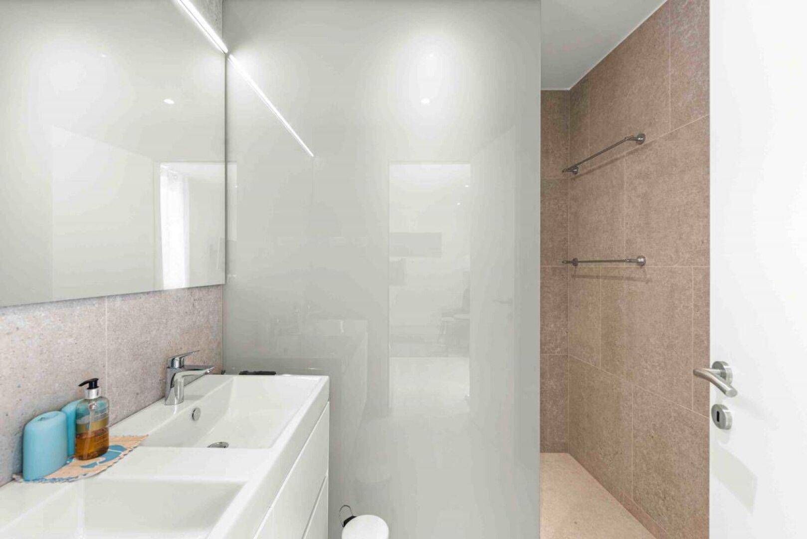 Modernes Badezimmer mit Einzelwaschbecken und eleganter Glasabtrennung.