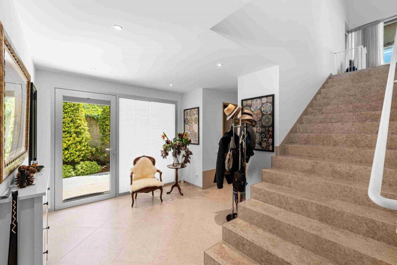 Heller Eingangsbereich mit Treppe, dekorativen Elementen und direktem Gartenzugang.