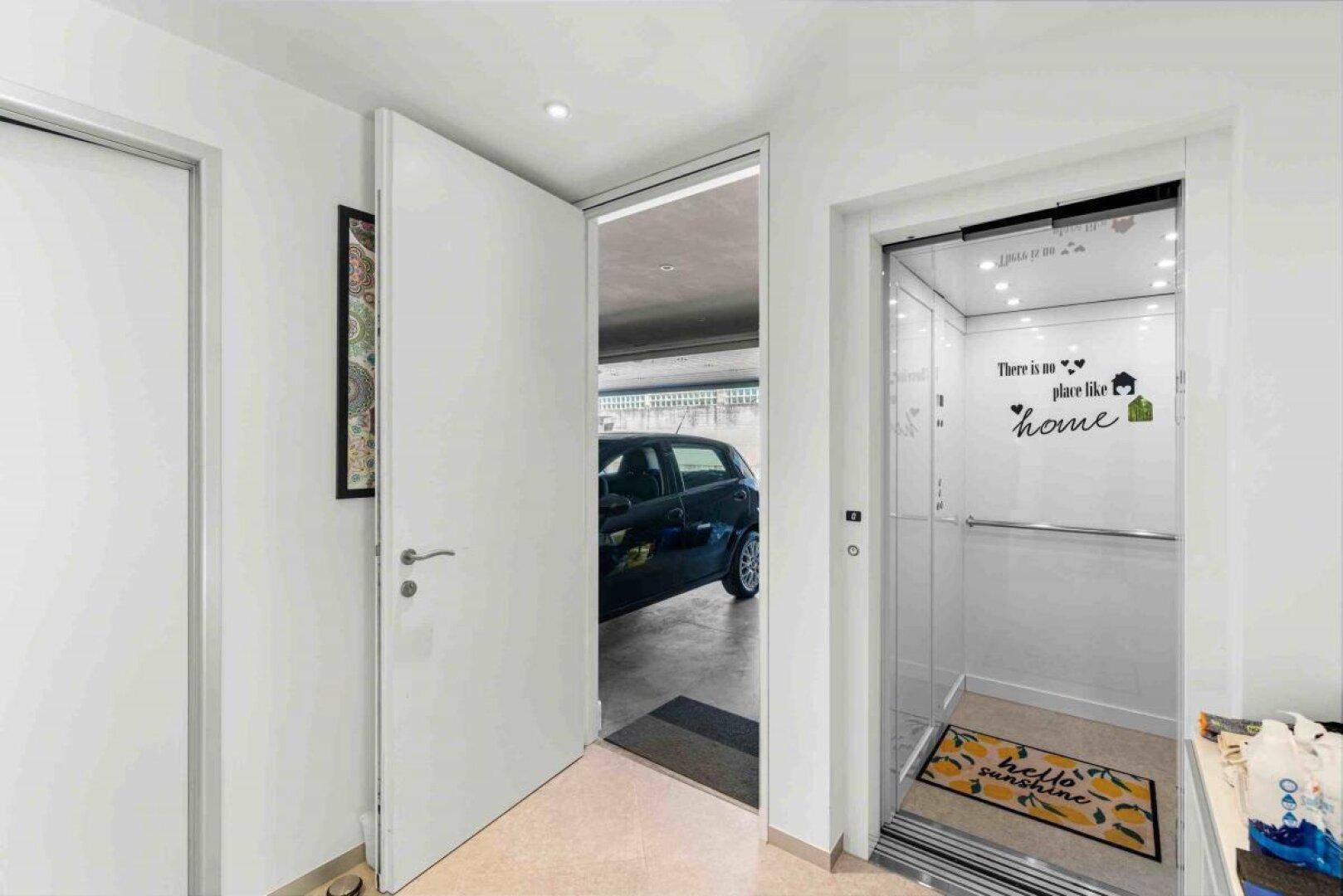 Moderner Flur mit offenem Aufzug und Blick in die angrenzende Garage.