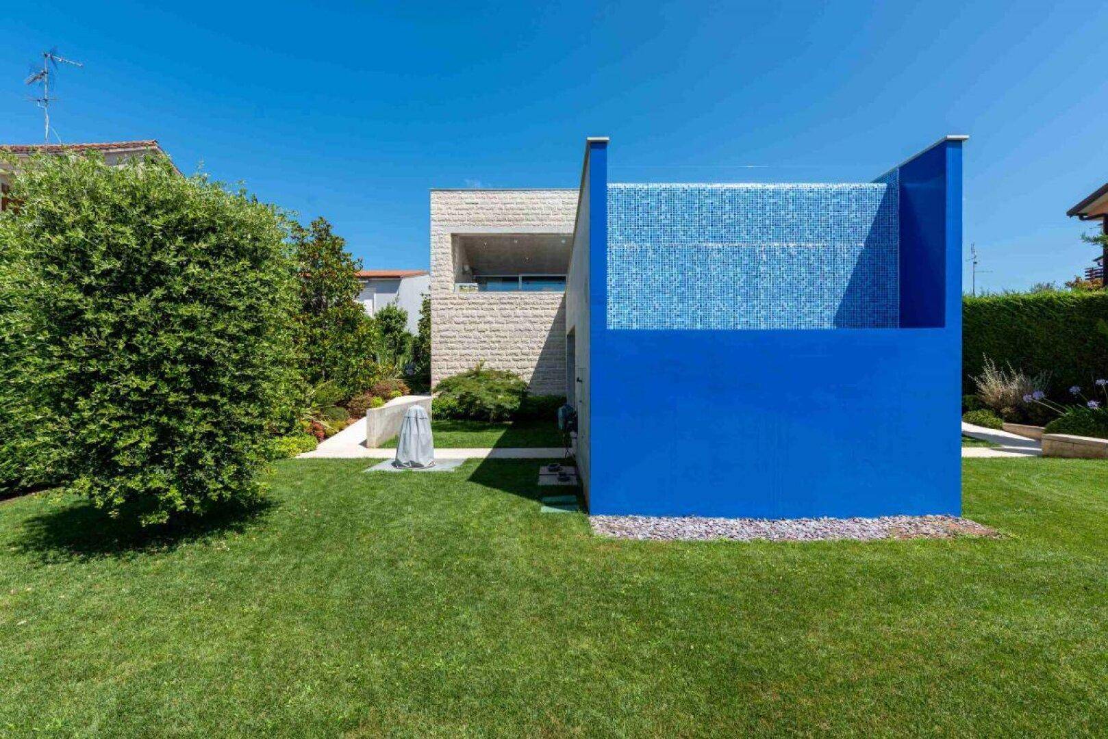Gartenansicht des Hauses mit einem auffälligen blauen Wasserspiel und gepflegtem Rasen.