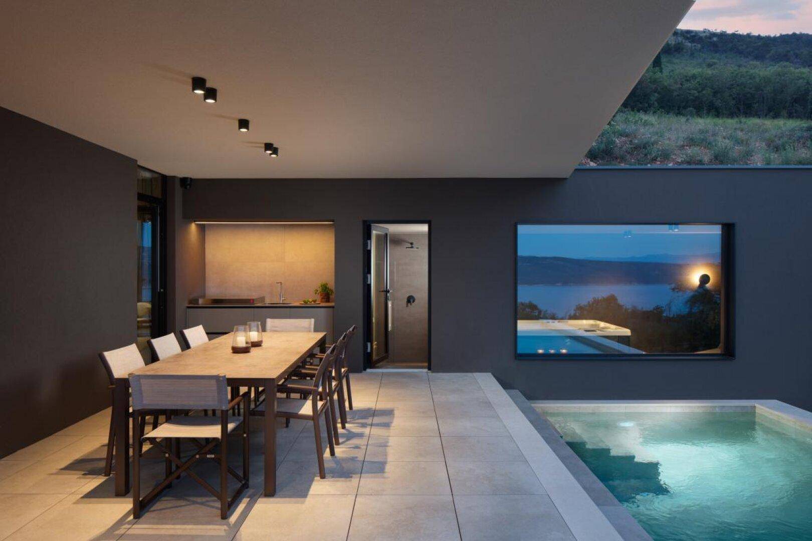 Geräumige Terrasse mit Esstisch, Außenküche, Dusche und kleinem Pool mit Meerblick.