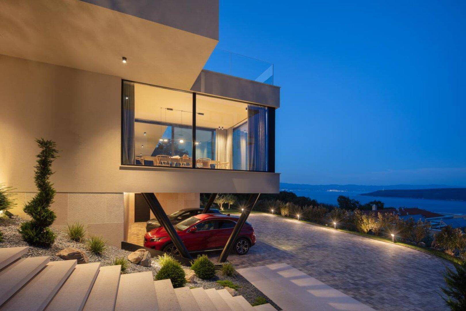 Architektonisch anspruchsvolle Villa mit Carport, Auffahrt und weitem Blick über die Küstenlandschaft.