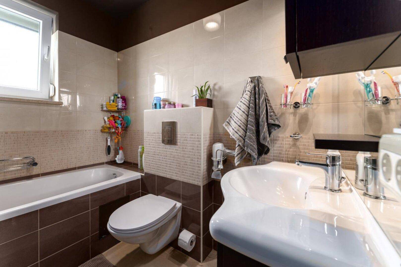 Badezimmer mit Badewanne, wandmontierter Toilette und großem Waschbecken.