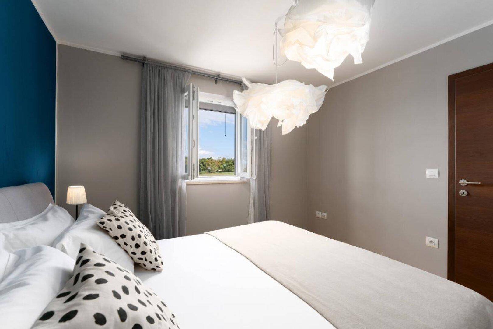 Gemütliches Schlafzimmer mit Fensterblick ins Grüne und moderner Einrichtung.