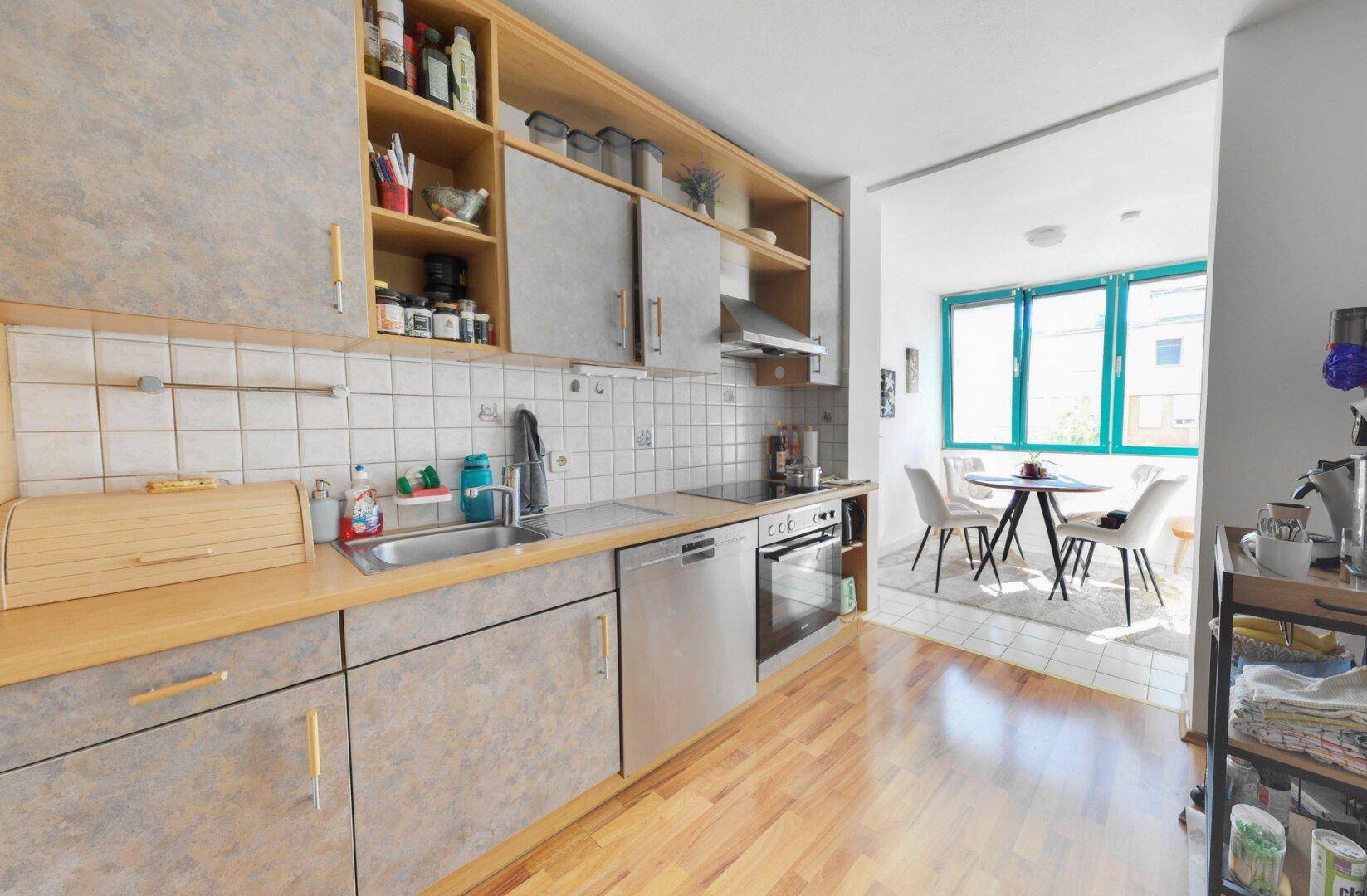 Funktionale Küche mit Holztheke, Einbaugeräten und angrenzendem Essbereich mit großen Fenstern.