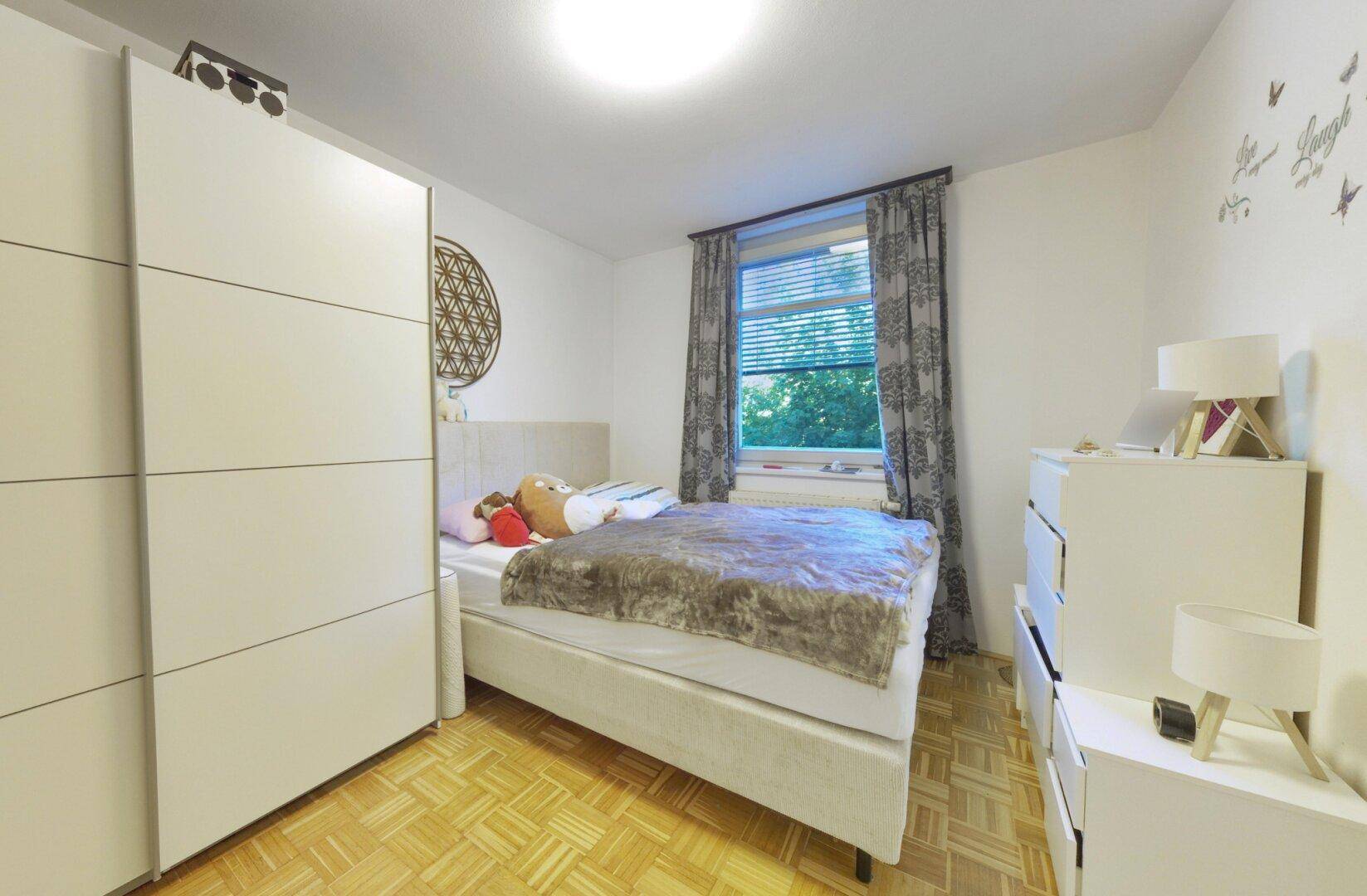 Helles Schlafzimmer mit Einzelbett, großem Kleiderschrank und Parkettboden, ideal für Gäste oder Kinder.