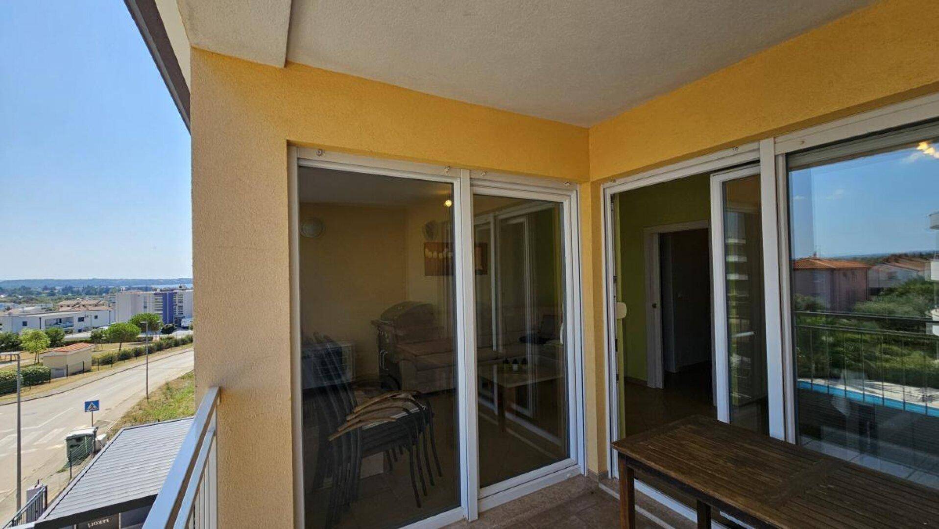 Balkon mit Schiebetüren zum Innenbereich und Blick auf die Straße und die umliegenden Gebäude.