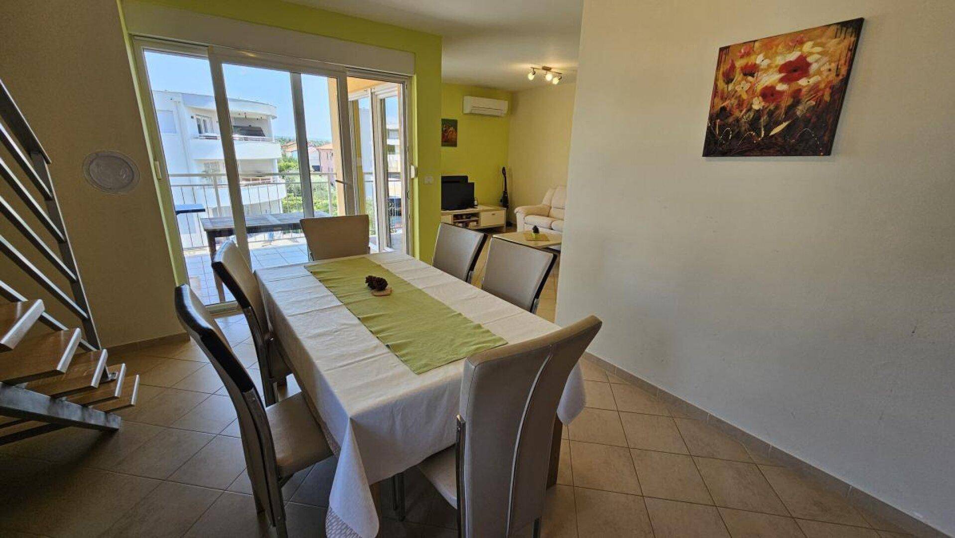 Heller Essbereich mit großem Tisch und Blick auf das Wohnzimmer und den Balkon.