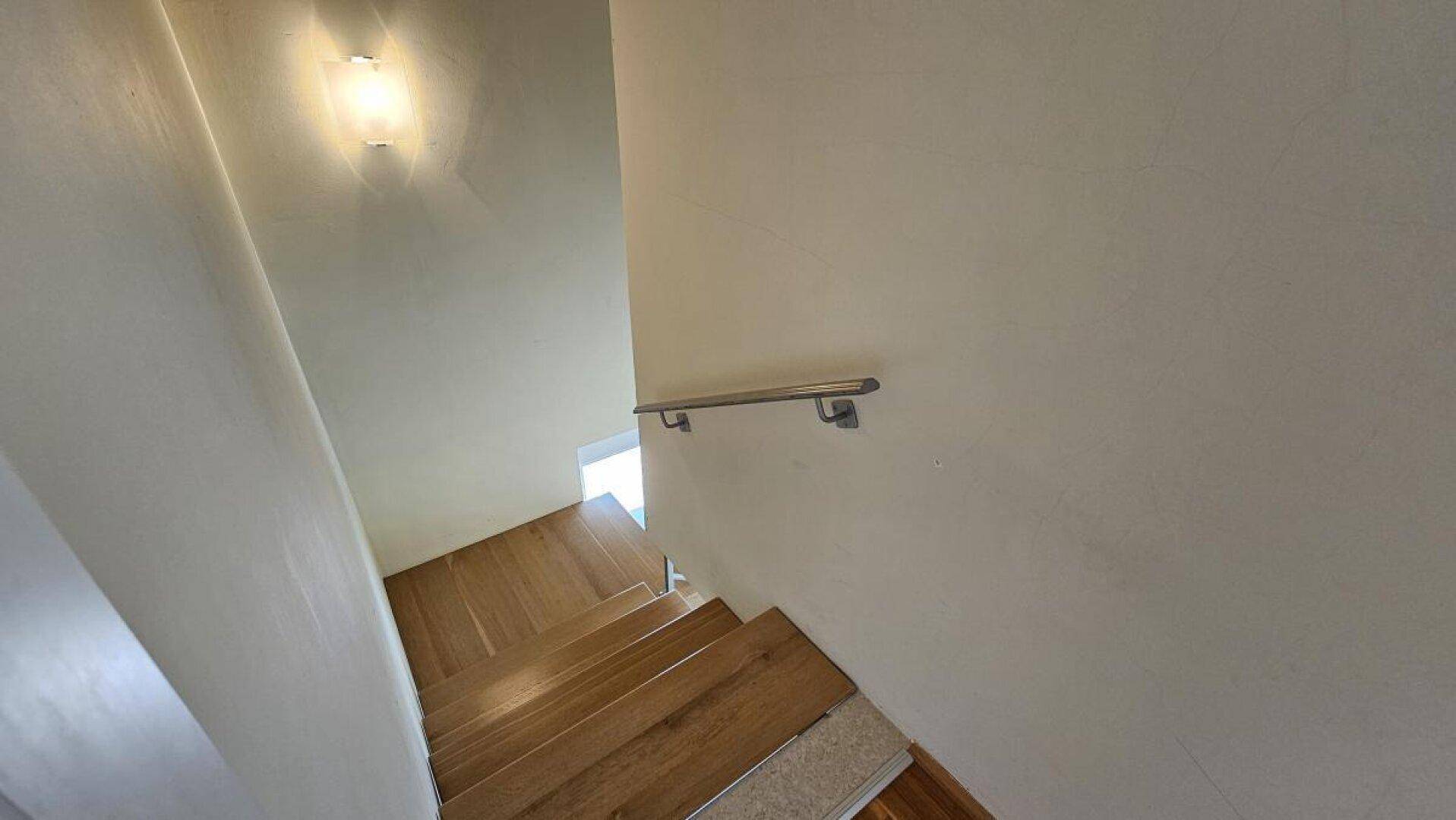 Holztreppe mit modernem Metallgeländer, die die verschiedenen Ebenen des Hauses verbindet.