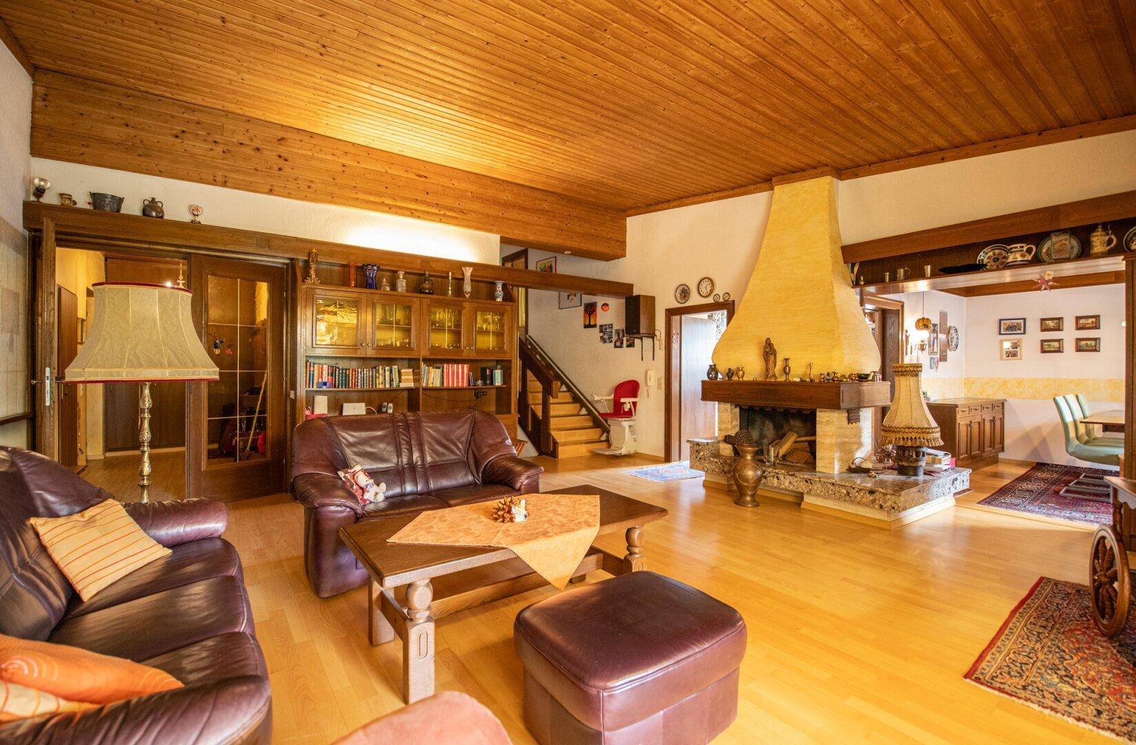 Gemütliches Wohnzimmer mit Holzbalkendecke, Kamin und traditionellen Möbeln, strahlt eine warme Atmosphäre aus.