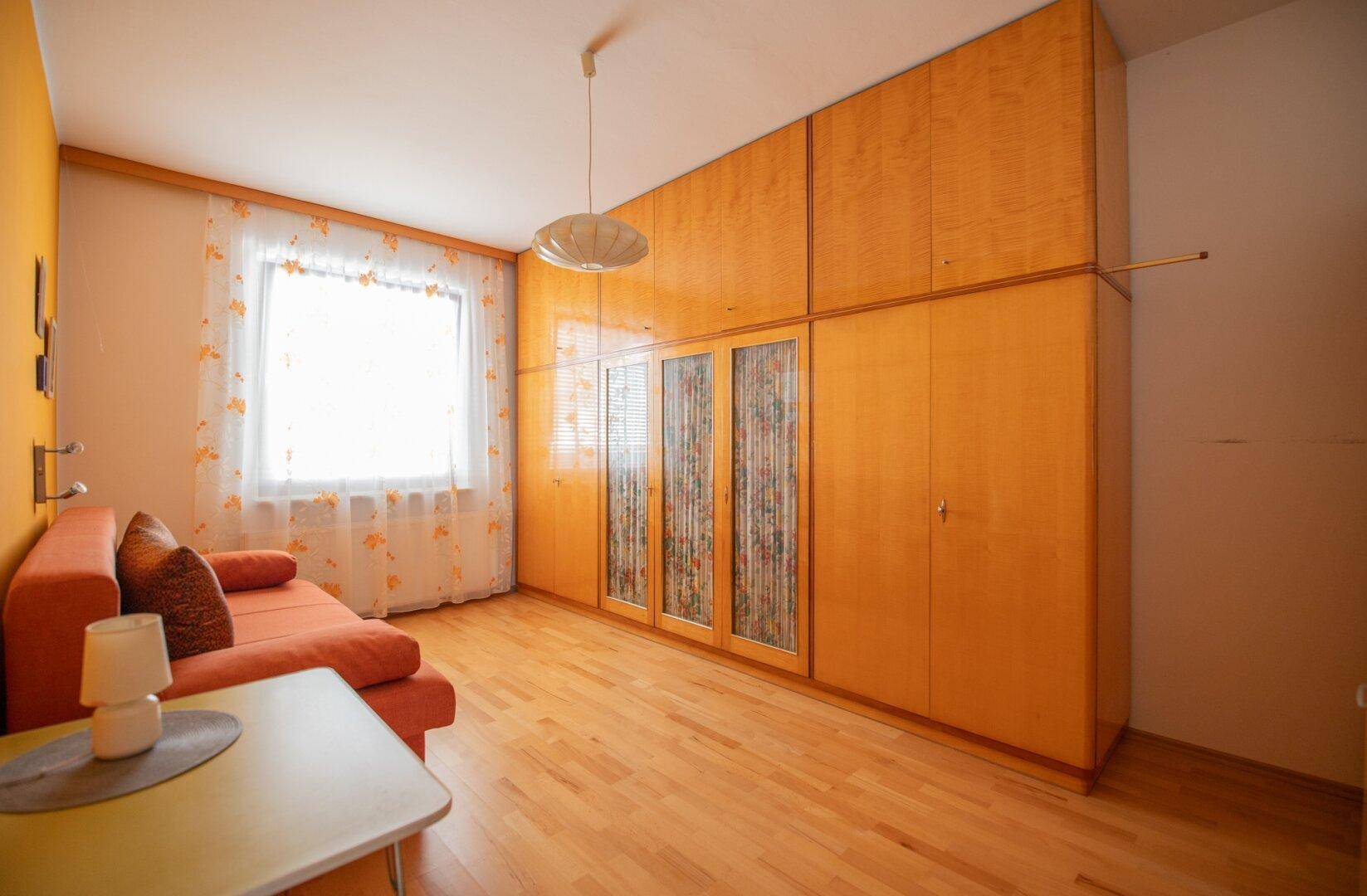 Helles Zimmer mit Holzfußboden und großem Einbauschrank, ideal als Schlaf- oder Gästezimmer nutzbar.
