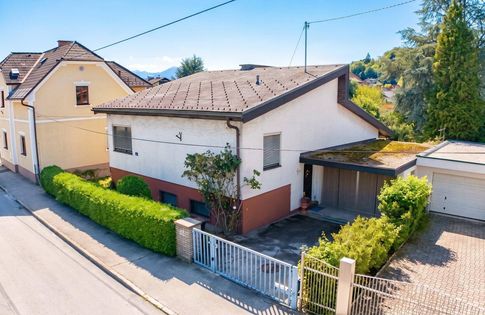 Ansicht des Hauses von der Straße mit Vorgarten, Einfahrt und Garage unter blauem Himmel.