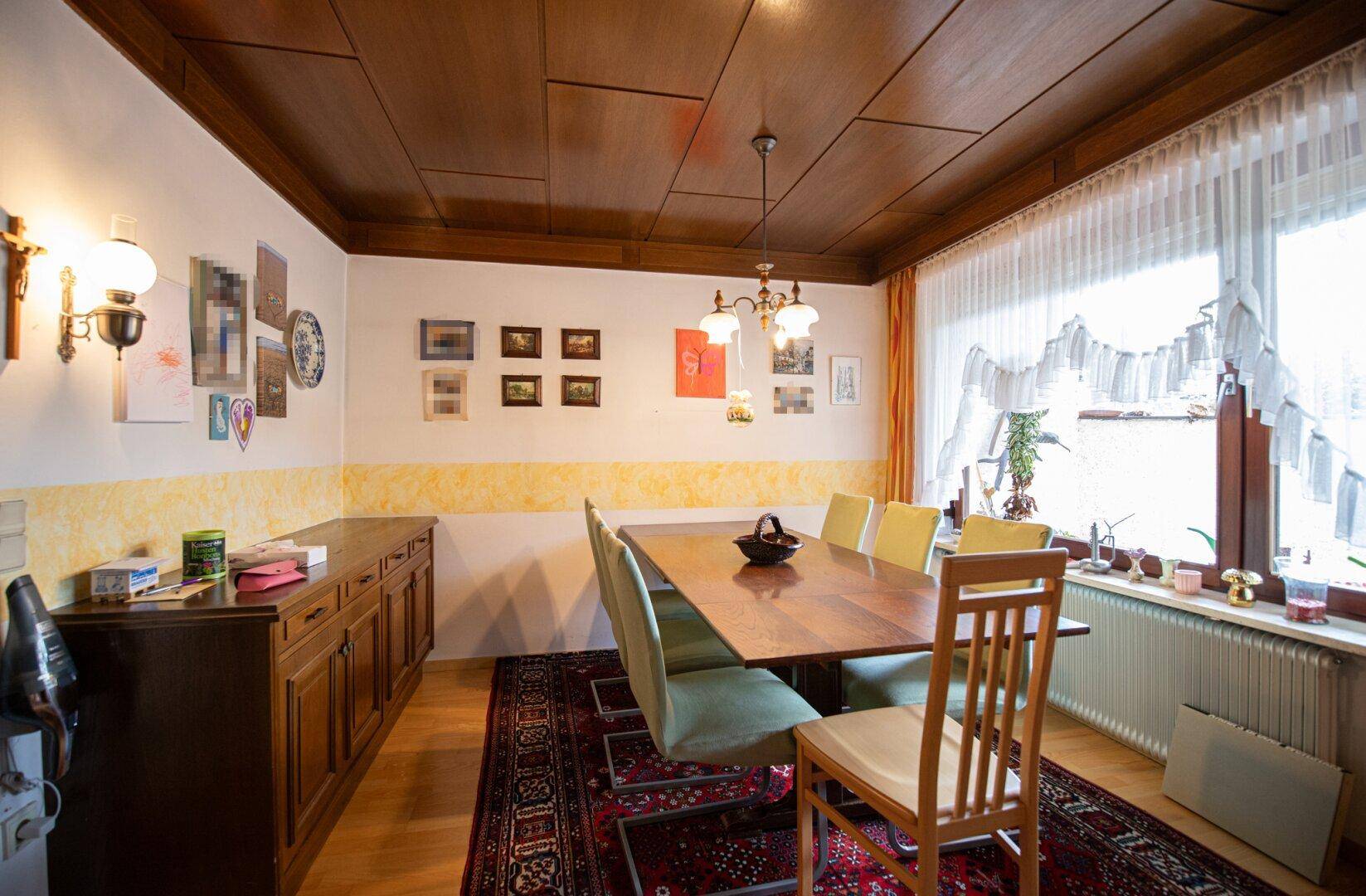 Traditioneller Essbereich mit Holztisch, passenden Stühlen und dunkler Holzdecke, ideal für Familienessen.
