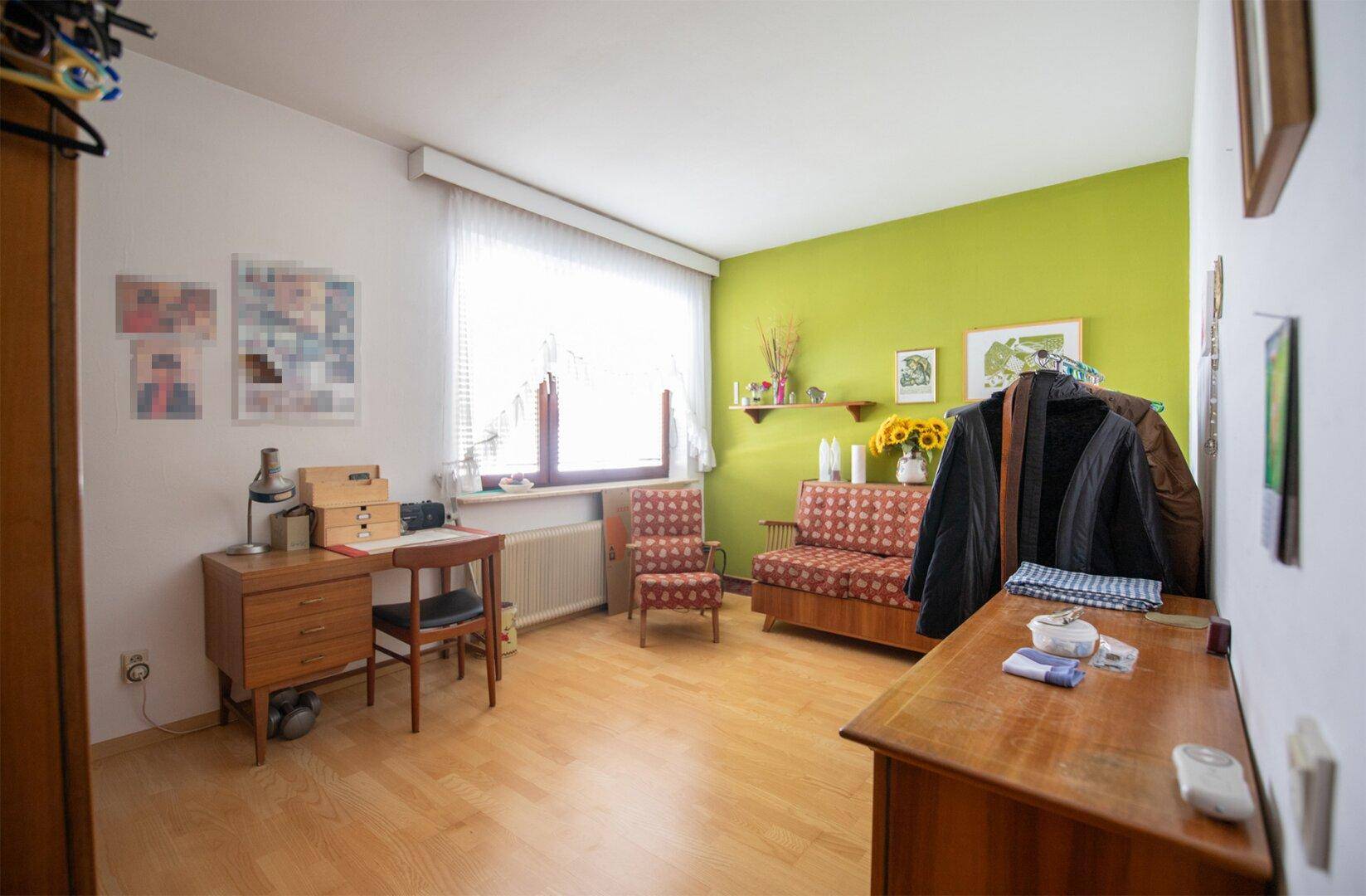 Helles Arbeitszimmer mit grün akzentuierter Wand, Holzfußboden und großem Fenster, bietet eine angenehme Arbeitsumgebung.