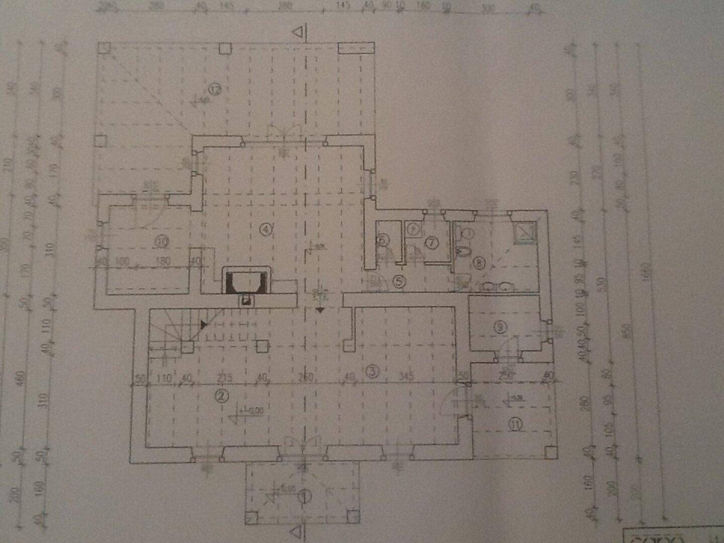 Grundriss des Erdgeschosses mit mehreren Räumen, Kamin und Zugang zu einem Außenbereich.