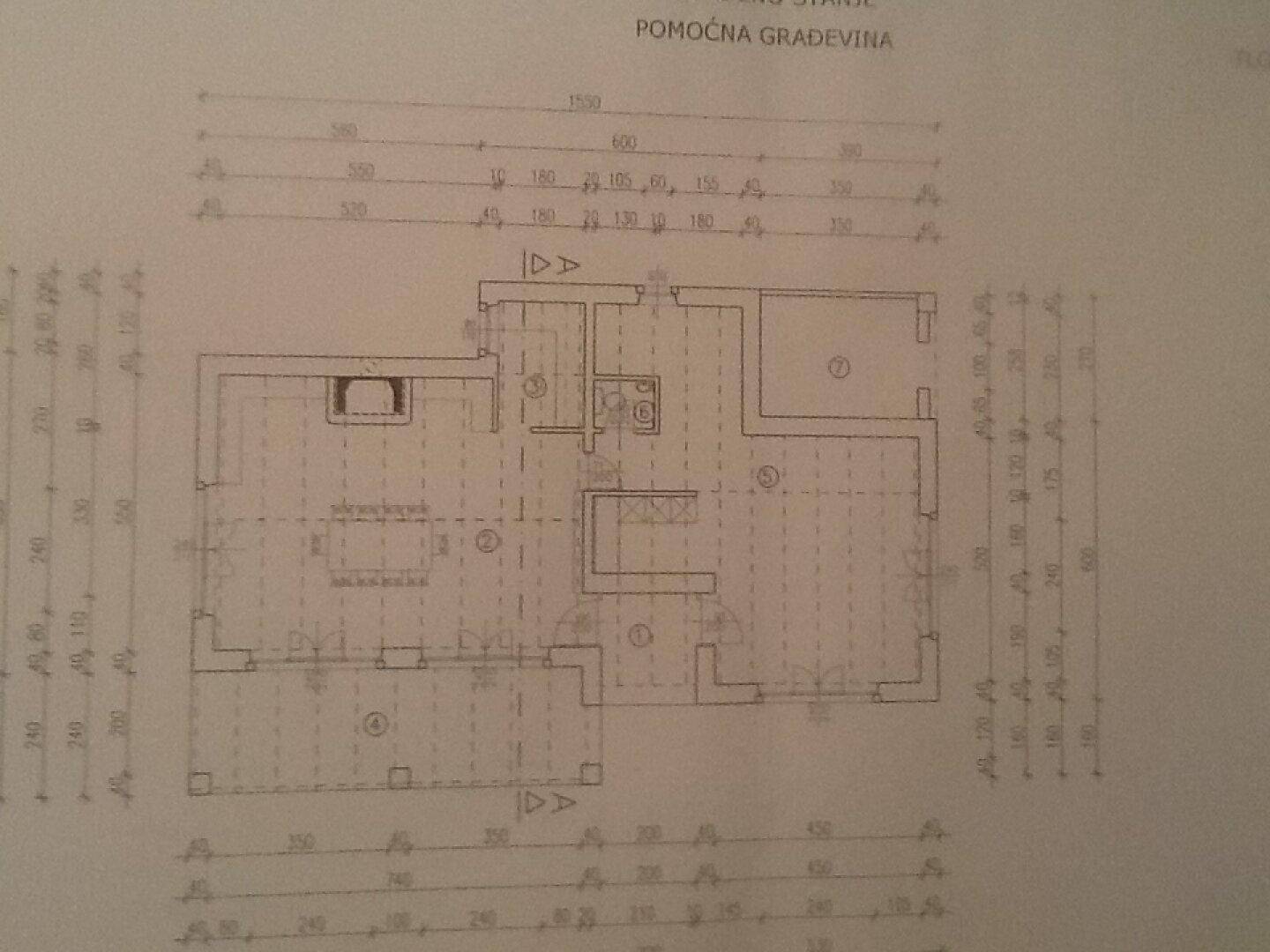 Grundriss des Erdgeschosses eines Nebengebäudes mit Küche, Wohnbereich und weiteren Räumen.