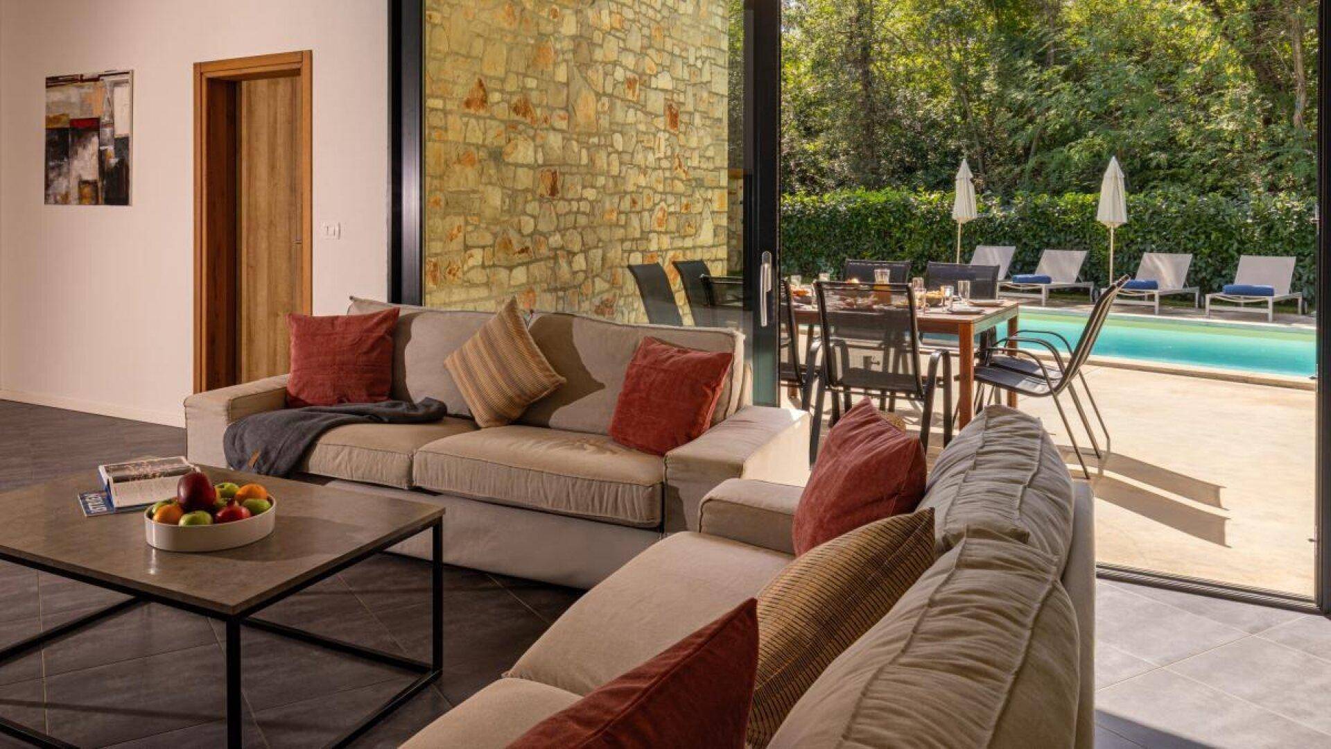 Gemütlicher Wohnbereich mit Sofas und direktem Zugang zur Terrasse und zum Poolbereich.