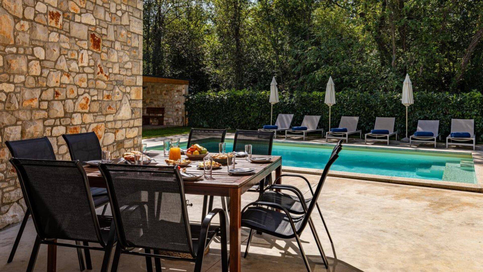 Einladender Essbereich im Freien auf der Terrasse mit Blick auf den Pool und die grüne Umgebung.