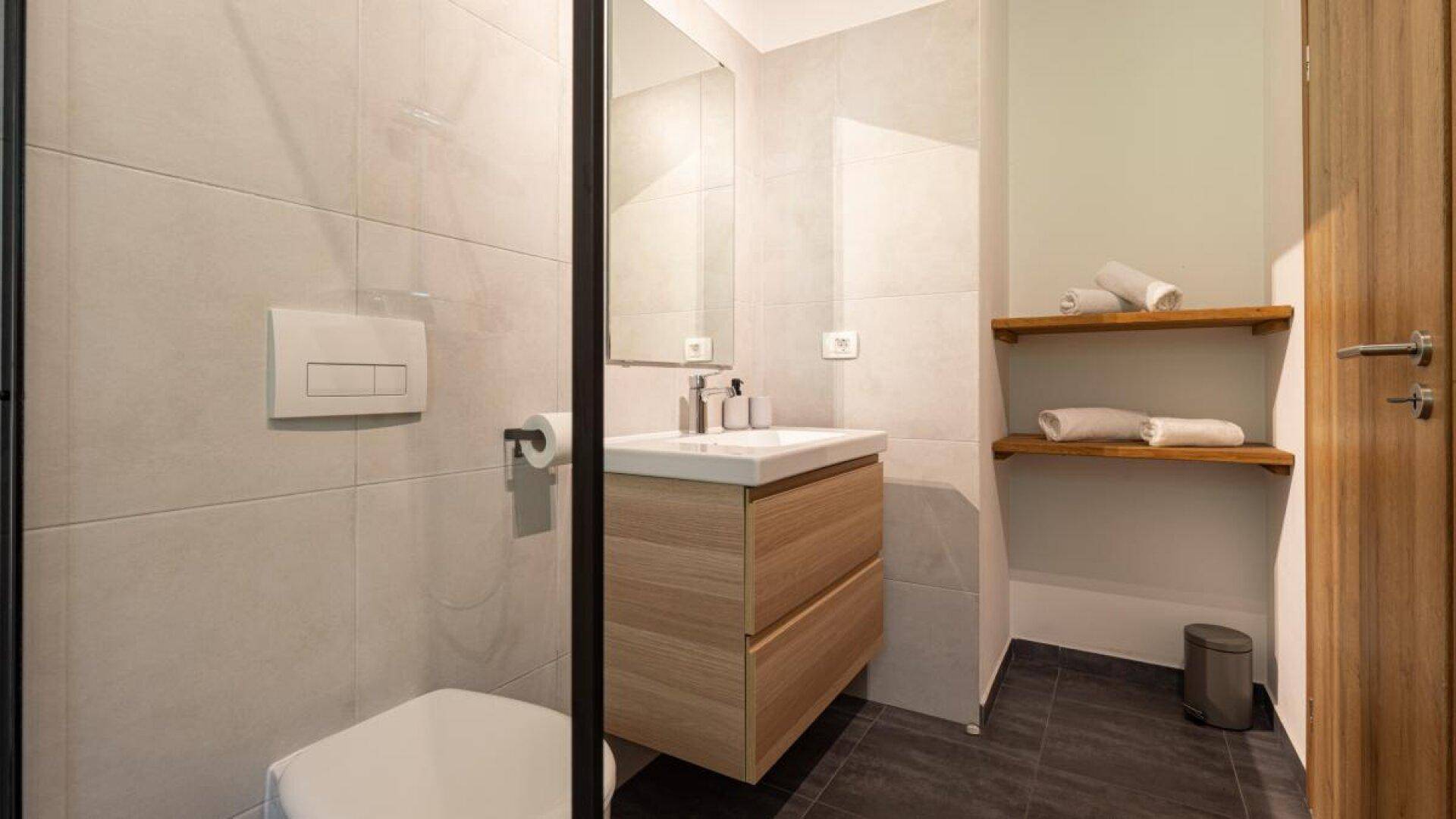 Modernes Badezimmer mit wandhängendem WC, Waschtischunterschrank und begehbarer Dusche.