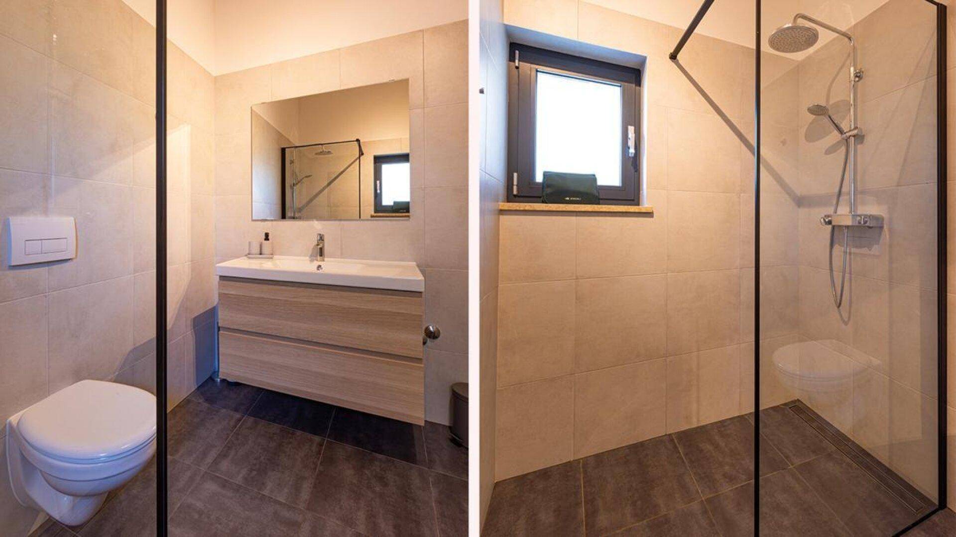 Modernes Badezimmer mit Waschtisch, Spiegel, wandhängendem WC und begehbarer Dusche.