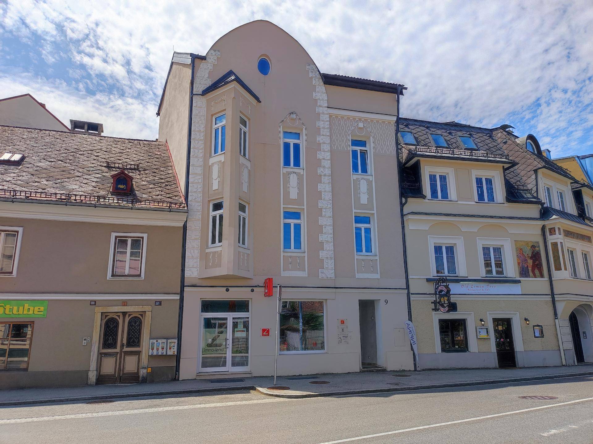 Die Vorderseite des Gebäudes mit Erker und dekorativen Elementen unter blauem Himmel.