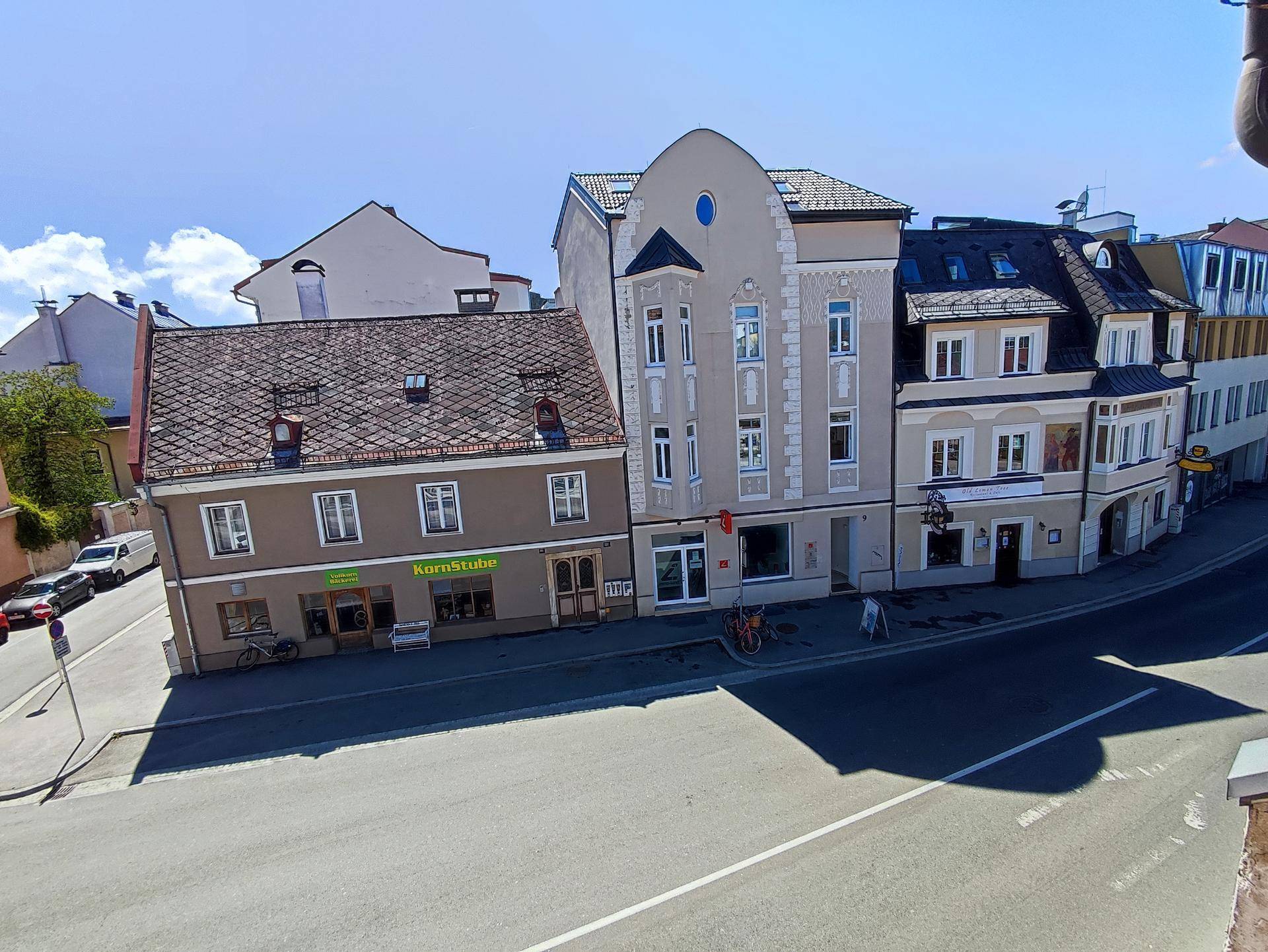Blick von oben auf eine belebte Straße mit mehreren Gebäuden und Geschäften in der Umgebung.