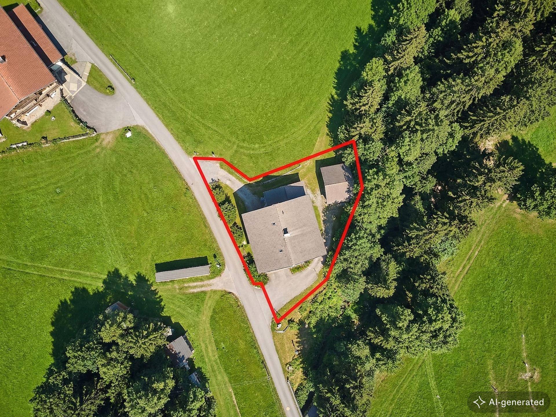 Draufsicht auf das Grundstück mit Wohnhaus und Nebengebäude, umgeben von grünen Wiesen.