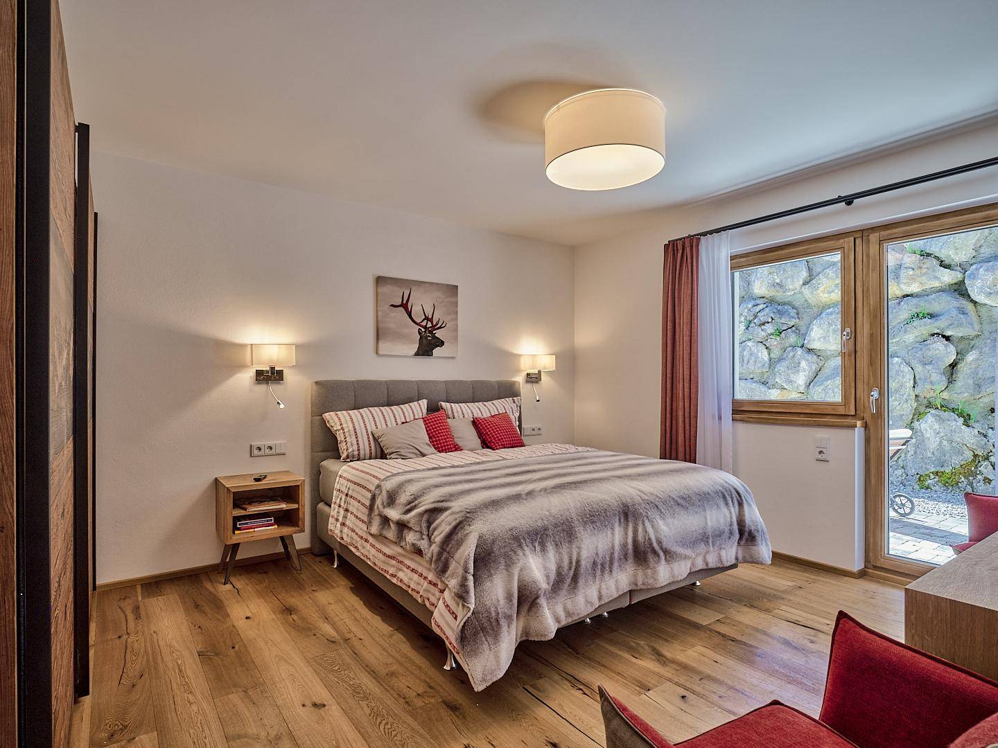 Gemütliches Schlafzimmer mit Holzboden, Doppelbett und Zugang zu einem kleinen Außenbereich mit Felsen.
