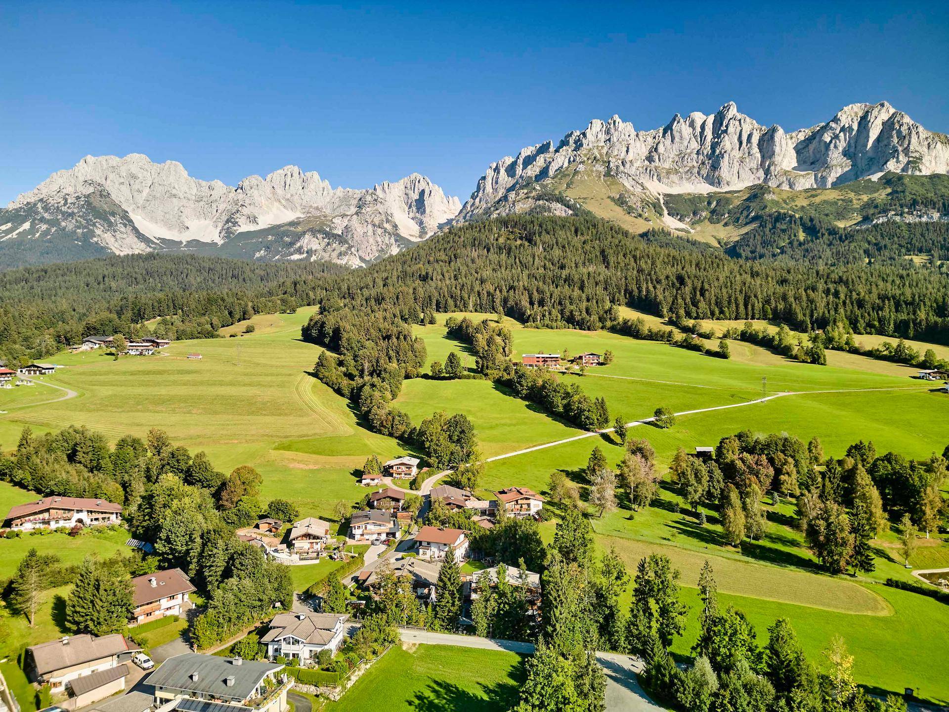 Panoramablick aus der Vogelperspektive auf ein idyllisches Dorf in den Alpen mit majestätischen Bergen.