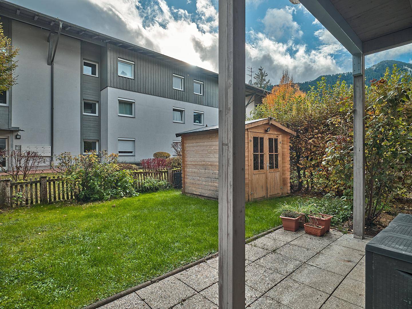 Gepflegter Gartenbereich mit Rasenfläche, Terrasse und einem kleinen Gartenhaus.