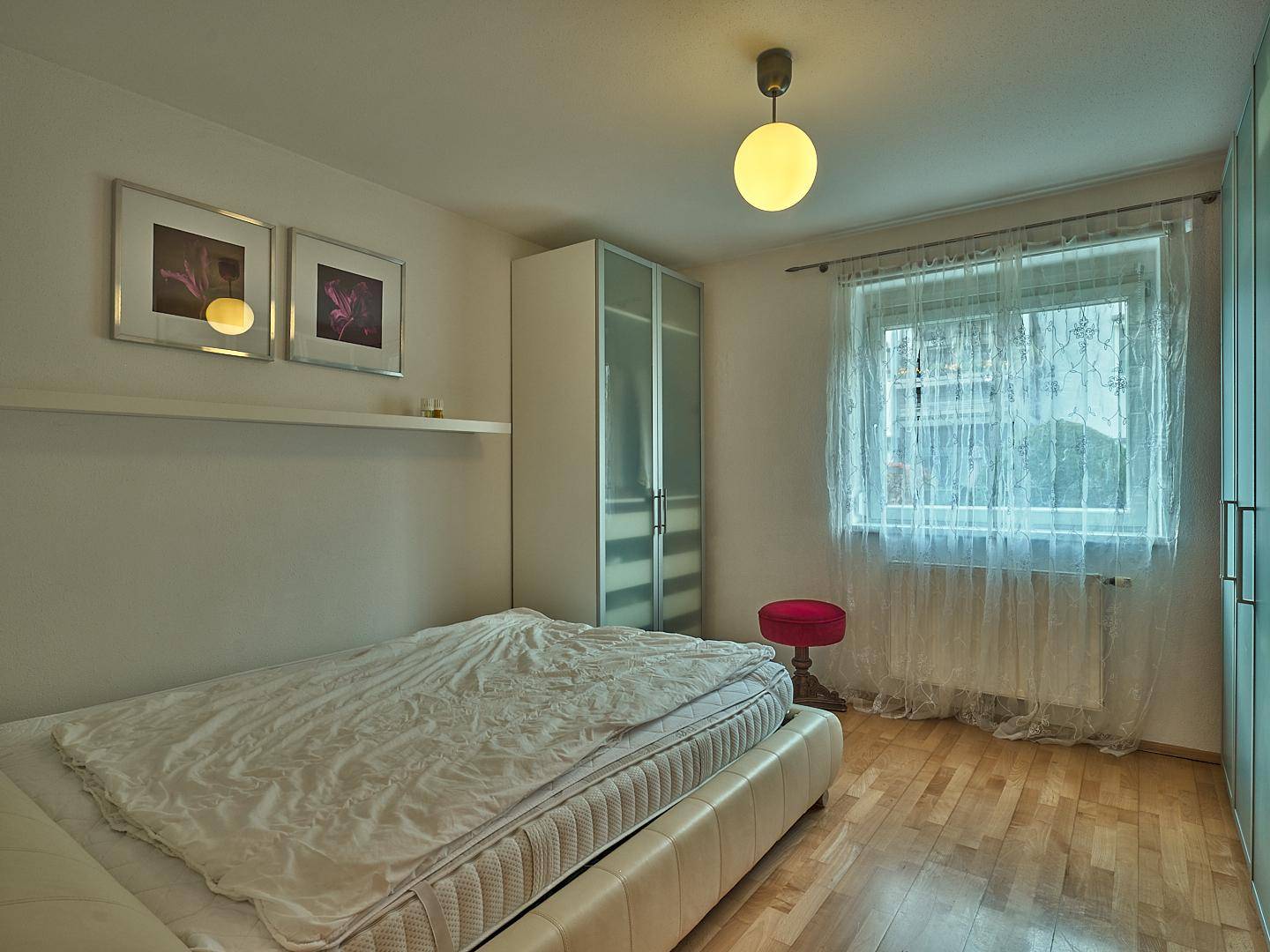 Helles Schlafzimmer mit Holzboden, großem Bett und Kleiderschrank.
