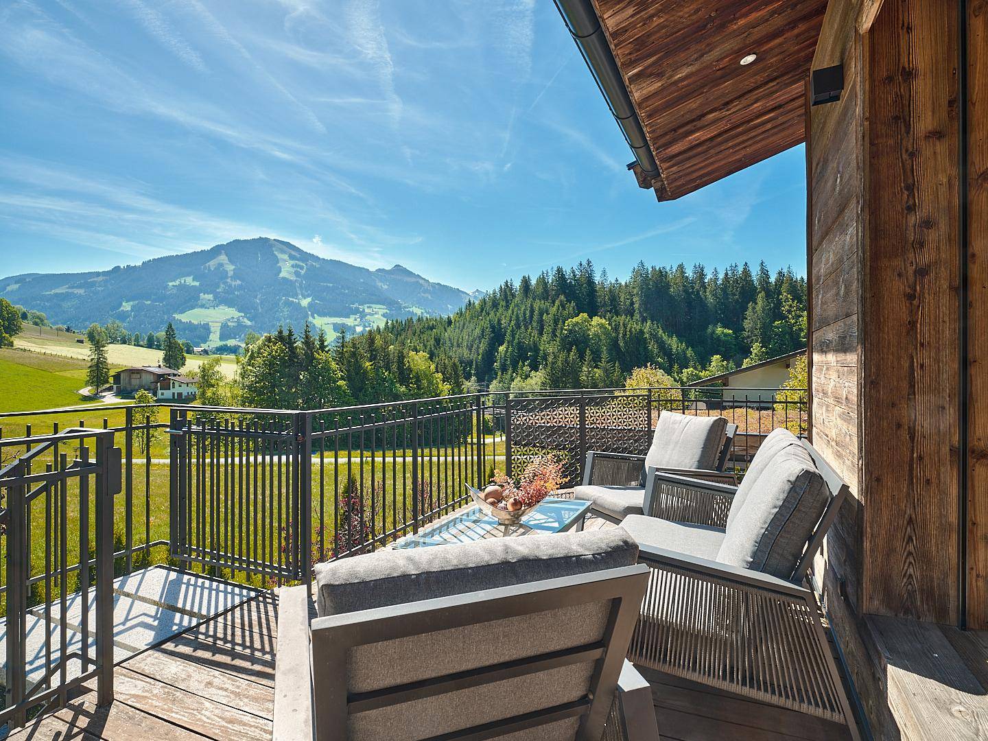 Gemütlicher Balkon mit bequemen Sitzgelegenheiten und einem weiten Blick auf die umliegende Berglandschaft.