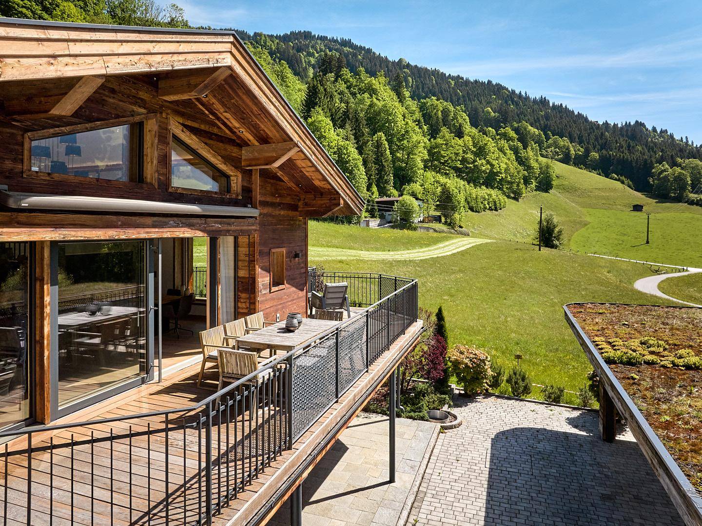 Charmantes Holzchalet mit großem Balkon, der einen Panoramablick auf die grünen Berge bietet.