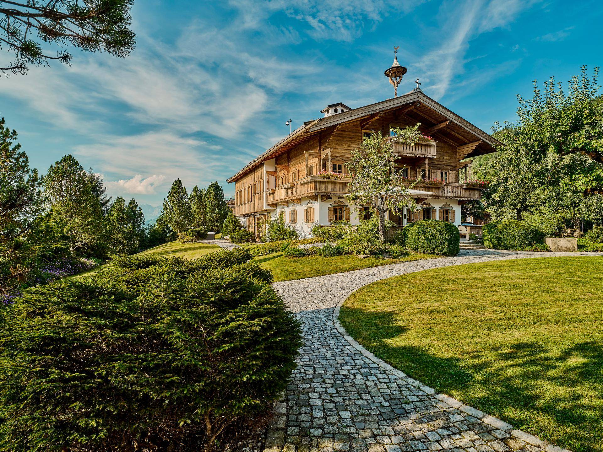 Charmantes Holzchalet umgeben von einem gepflegten Garten mit Rasenflächen und geschwungenem Steinweg.