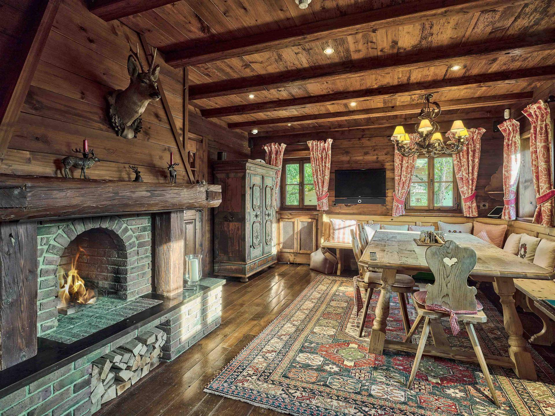 Gemütlicher Essbereich im Landhausstil mit Kamin, Holzbalken und traditionellem, farbenfrohem Teppich.
