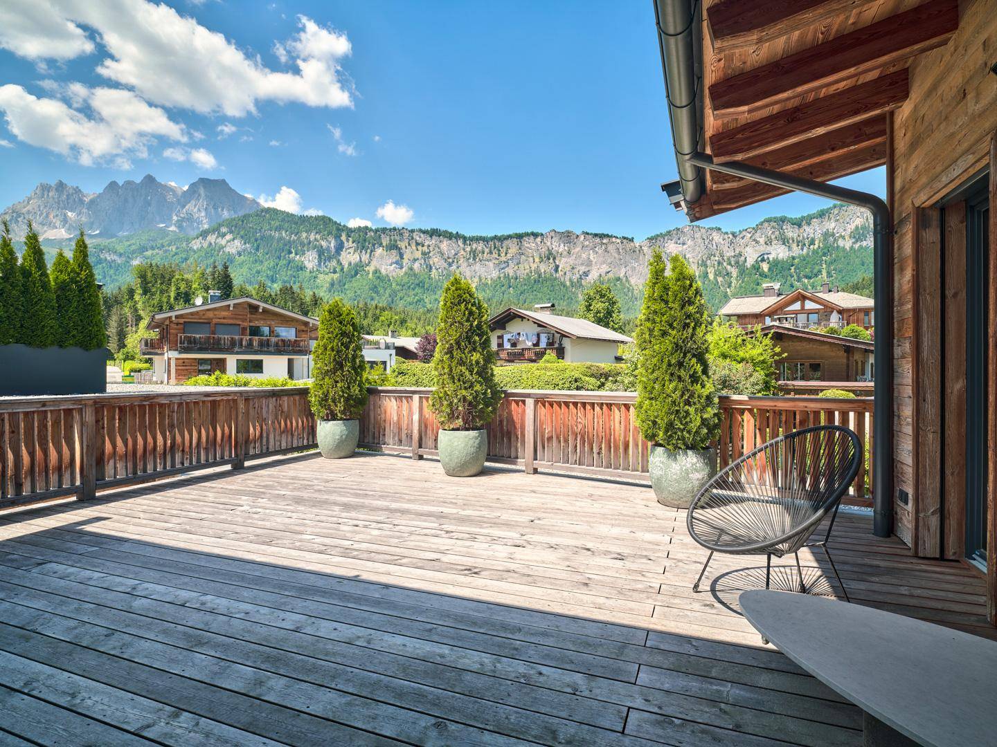 Geräumige Holzterrasse mit Sitzgelegenheiten und atemberaubendem Blick auf die Berge.