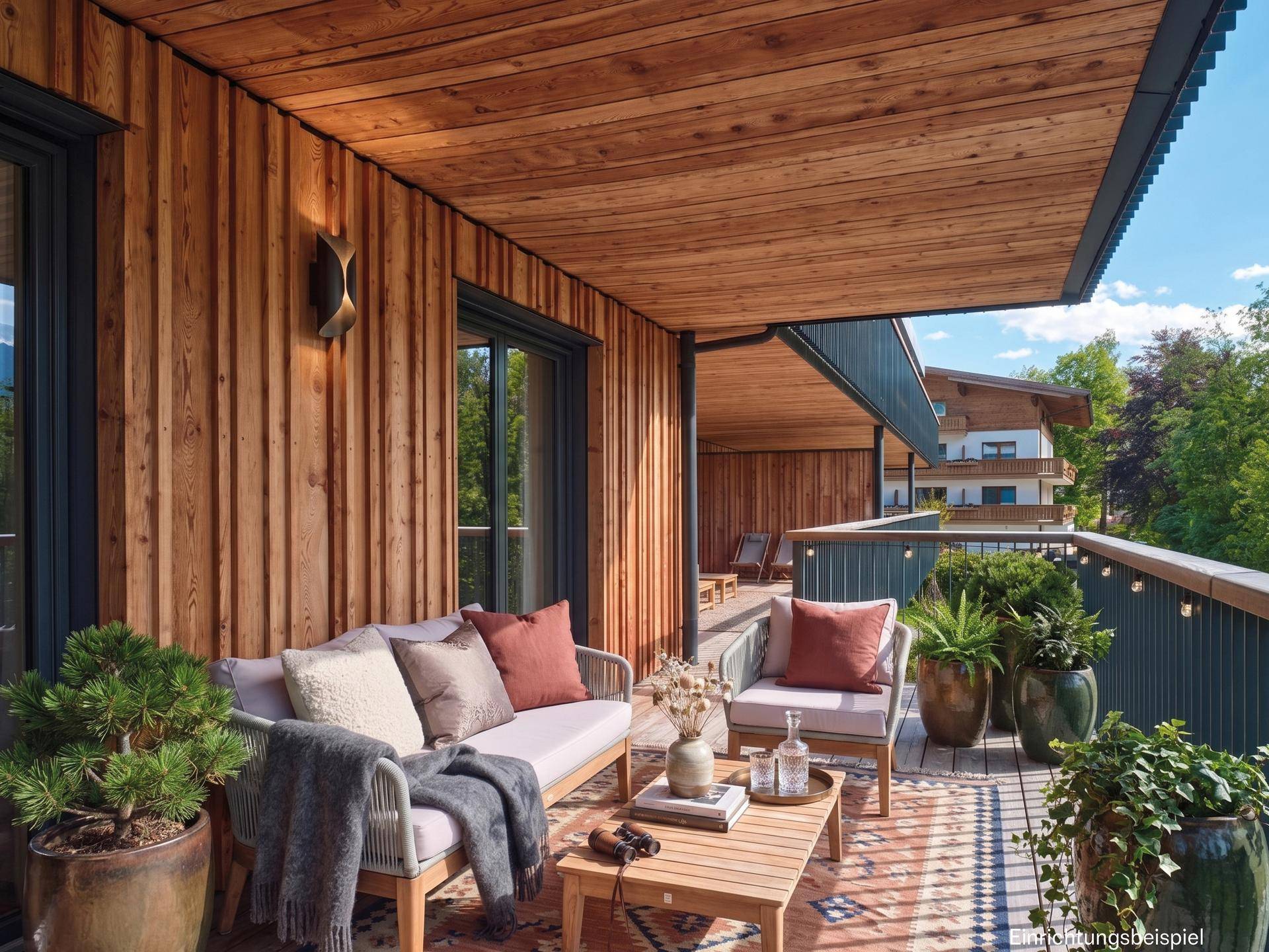 Möblierter Balkon mit Holzverkleidung und Blick auf die umliegende Natur und Gebäude.