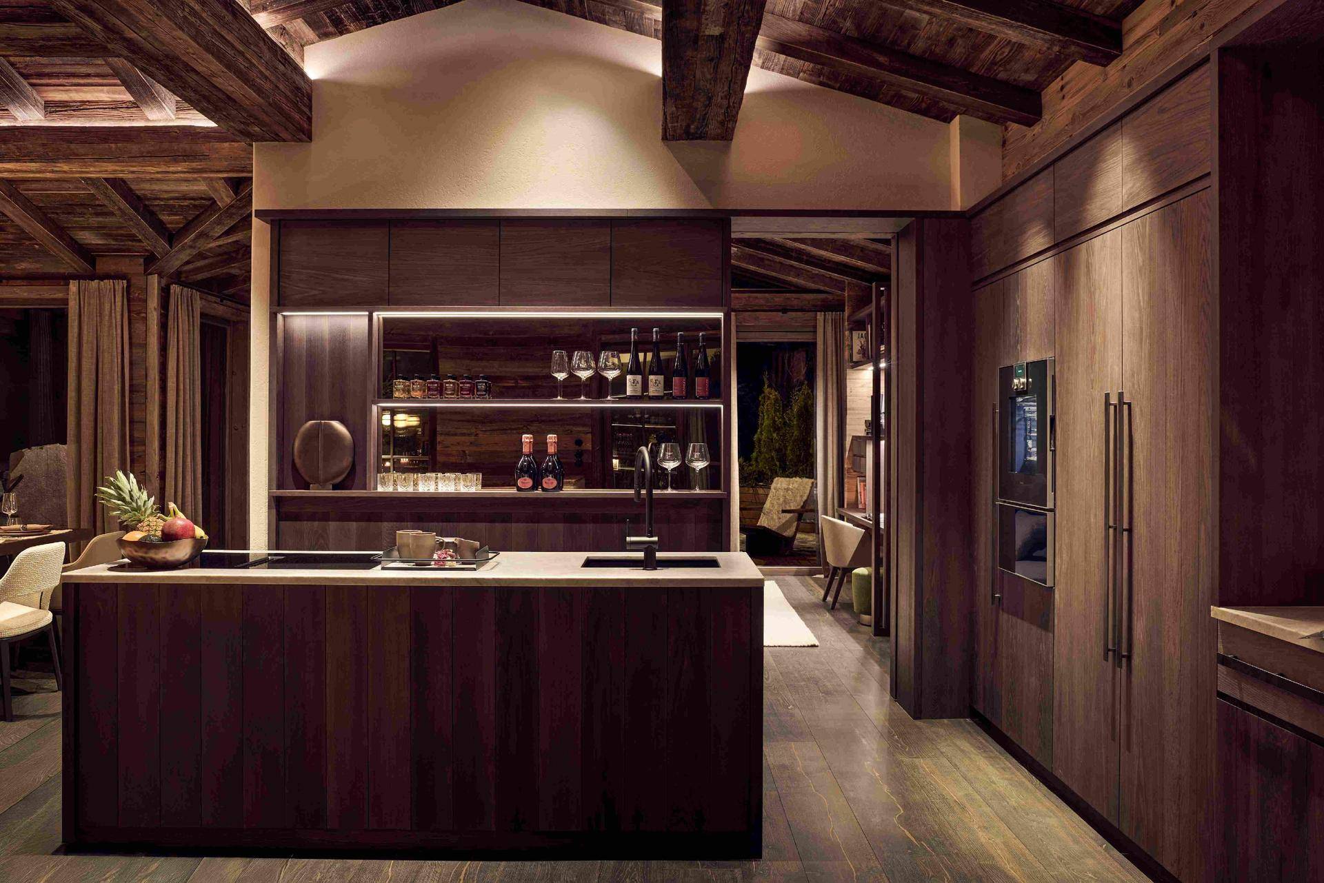 Moderne Holzküche mit Kücheninsel, integrierten Premium-Geräten und viel Stauraum im alpinen Design.