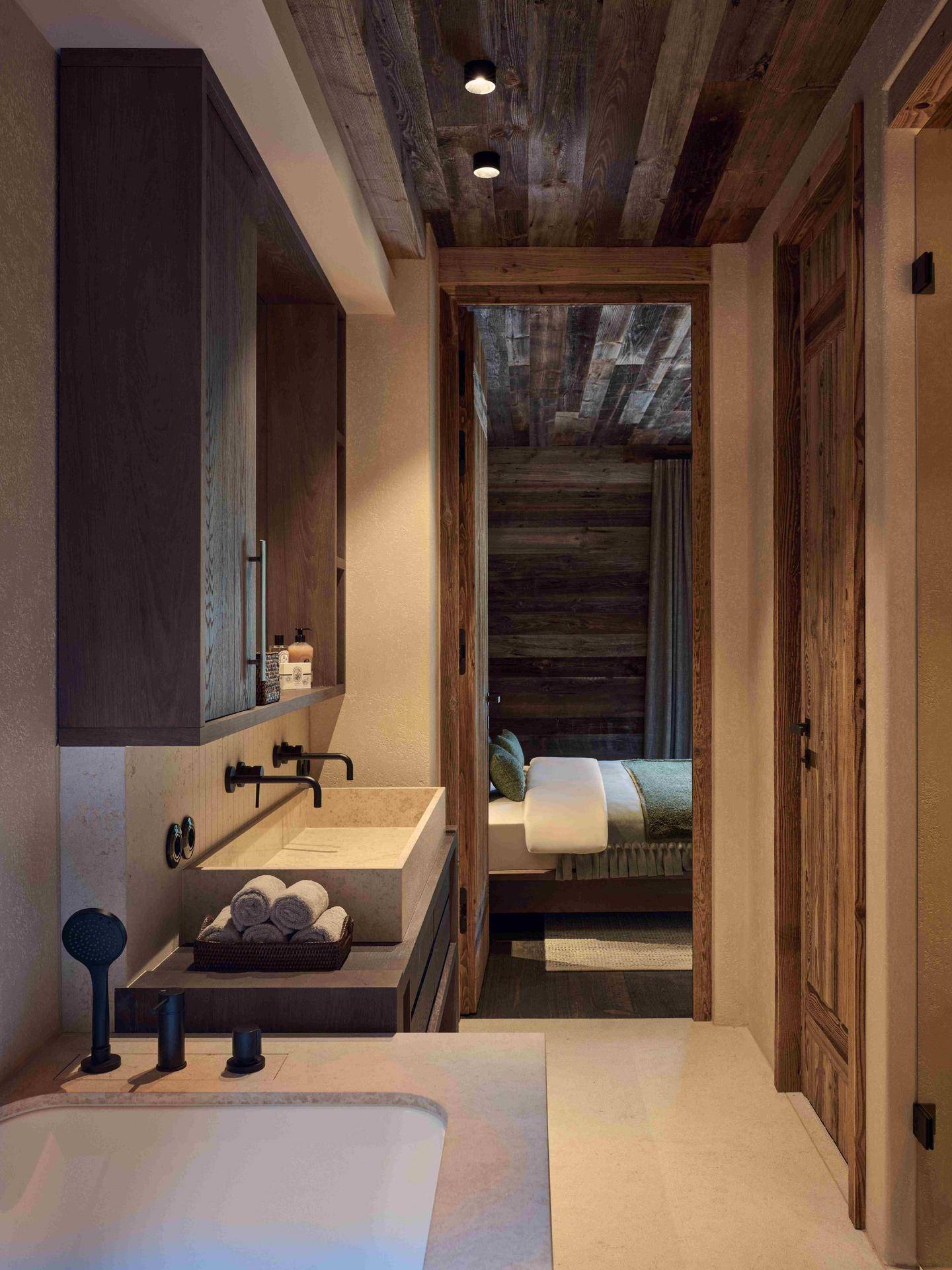 Modernes Badezimmer mit Badewanne, Einzelwaschbecken und direktem Zugang zum Schlafzimmer.